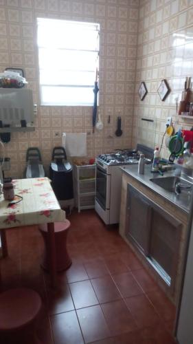 uma cozinha com um fogão, um lavatório e uma mesa em Quarto Casal próximo ao Sambódromo-RJ no Rio de Janeiro