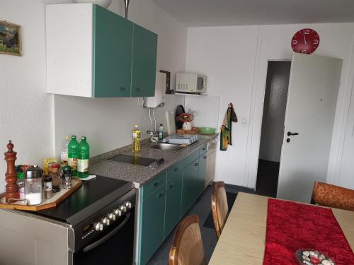 uma cozinha com armários verdes e uma mesa com mesa; em TWS Pension an der B1 em Magdeburg