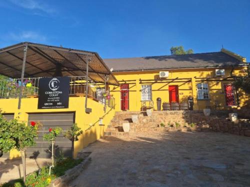 a yellow building with red doors and a sign at Cobblestone Court in Colesberg