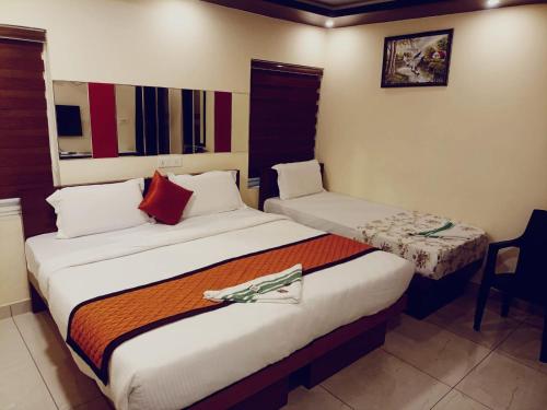 a hotel room with two beds and a chair at Majestic Inn in Trivandrum