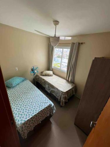 una camera da letto con due letti e una finestra di Apto aconchegante veraneio em Torres/Rs a Torres