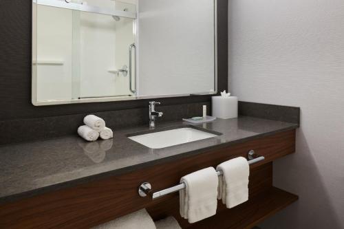 a bathroom with a sink and a mirror and towels at Courtyard by Marriott Los Angeles Westside in Los Angeles