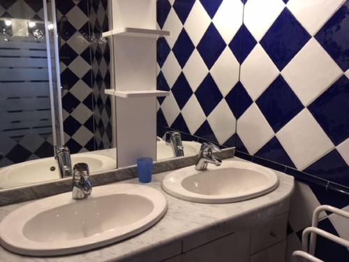- deux lavabos dans une salle de bains revêtue de carrelage bleu et blanc dans l'établissement Chalet Bassin d'Arcachon Parc Résidentiel Loisirs, à La Teste-de-Buch