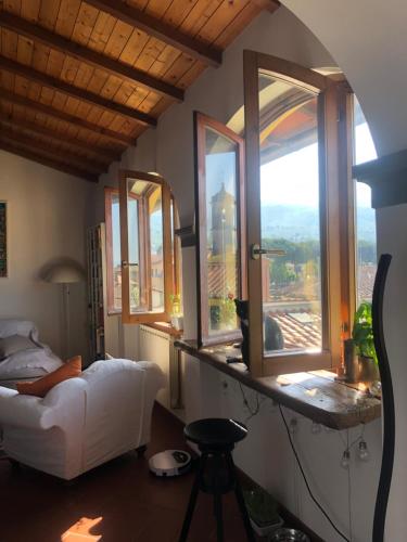 uma sala de estar com um sofá branco e janelas em Sotto le stelle delle balze em Castelfranco di Sopra