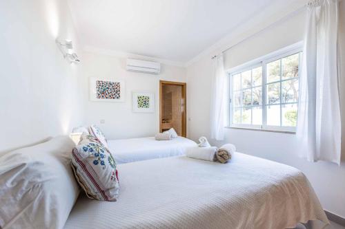 2 Betten in einem weißen Zimmer mit Fenster in der Unterkunft Villa Tamara in Olhos de Água