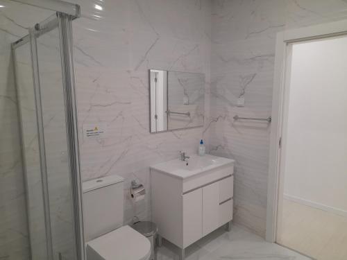 a white bathroom with a toilet and a sink at Casa da Praça in Murtosa