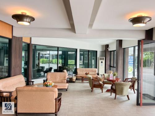 a lobby with chairs and tables and windows at Buritel Hotel in Buriram