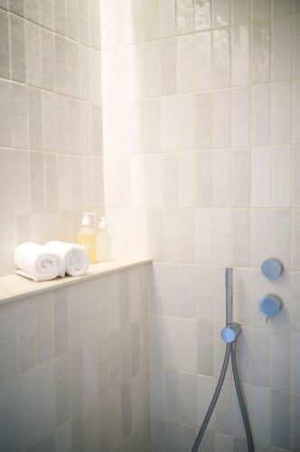 a bathroom with white tiled walls and a shelf with towels at Maison La Grande Ourse in Beaucens