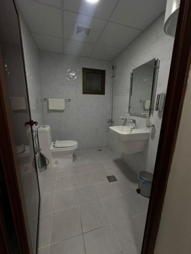 a white bathroom with a toilet and a sink at الساعه 60 الفندقيه in Dammam