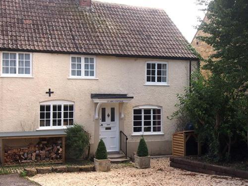 a white house with a cross on the door at Clare Cottage in Sherborne