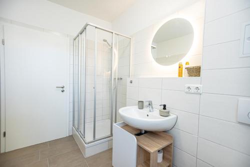 a white bathroom with a sink and a shower at Bloßfeld-Apartments Geräumige Stadtoase mitten im Zentrum mit 3 Schlafzimmern, Gratis Parkplatz, W-Lan, Netflix in Jena