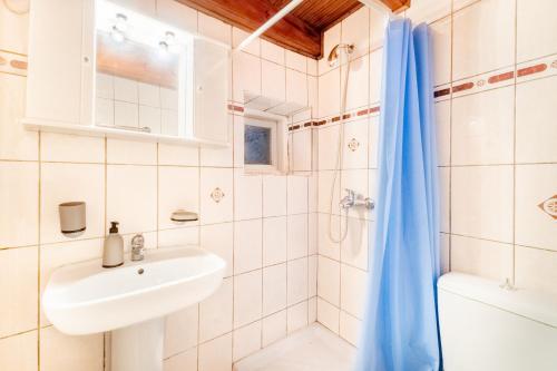 y baño blanco con lavabo y ducha. en Sinarades Village House, en Sinarádes