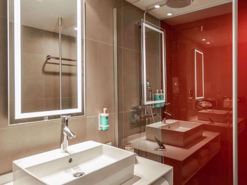 La salle de bains est pourvue de 2 lavabos et d'un grand miroir. dans l'établissement Novotel Valence Sud, à Valence