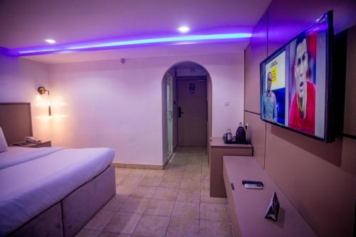 Pokój z łóżkiem i telewizorem na ścianie w obiekcie WELLINGTON HOTEL LIMITED w mieście Effurun