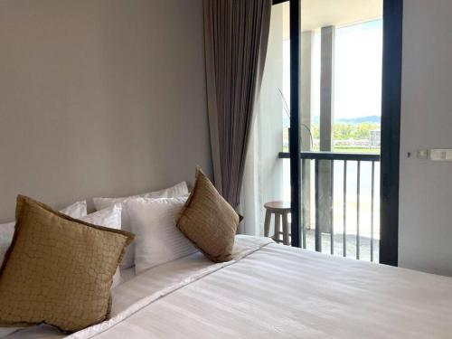 a bedroom with a bed with pillows and a balcony at Private apartment Zcape2 near Boat Avenue in Bang Tao Beach
