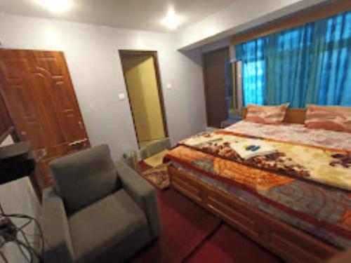 - une chambre avec un lit, une chaise et une fenêtre dans l'établissement Shiv Inn Stay Darjeeling, à Darjeeling