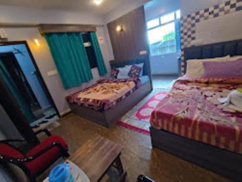une chambre d'hôtel avec deux lits et une chaise dans l'établissement Shiv Inn Stay Darjeeling, à Darjeeling