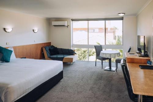 ein Hotelzimmer mit einem Bett, einem Schreibtisch und einem Tisch in der Unterkunft Best Western Chaffey Motor Inn in Mildura