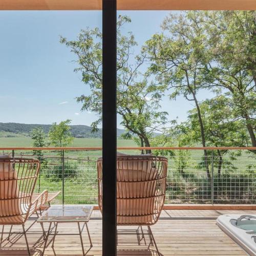 two chairs and a table on a deck with a view at Kapolcsi Sziklák in Vigántpetend