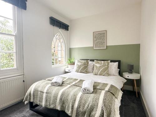 a bedroom with a large bed with two towels on it at Stylish & Spacious City Centre 3-Bed Townhouse with Private Walled Courtyard in Canterbury