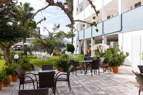 an outdoor patio with chairs and tables and trees at Zoe Seaside in Loutra Edipsou