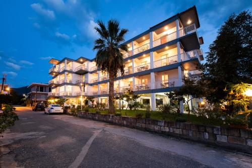 a building with a palm tree in front of a street at Zoe Seaside in Loutra Edipsou