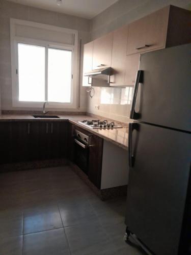 a kitchen with a refrigerator and a stove top oven at Alhoceima Ville Appartement in Al Hoceïma