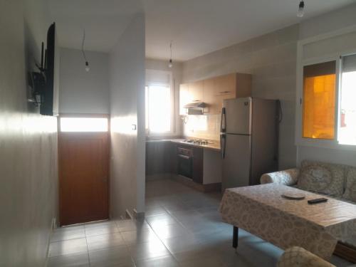 cocina con sofá, mesa y nevera en Alhoceima Ville Appartement en Alhucemas