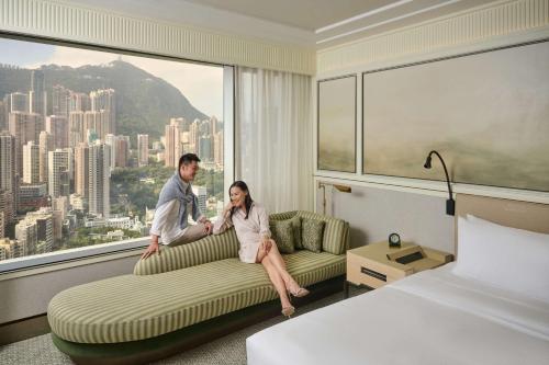 a man and woman sitting on a couch in a hotel room at Island Shangri-La, Hong Kong in Hong Kong