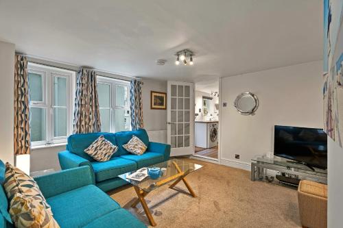 a living room with a blue couch and a tv at Finest Retreats - Porthole Cottage in Mevagissey