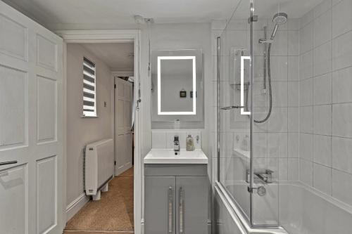 a white bathroom with a sink and a shower at Finest Retreats - Porthole Cottage in Mevagissey