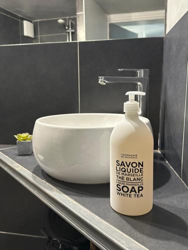 a bottle of soap sitting next to a bathroom sink at Home Cassis - Maison Les Calanques - Piscine chauffée à 30c in Cassis