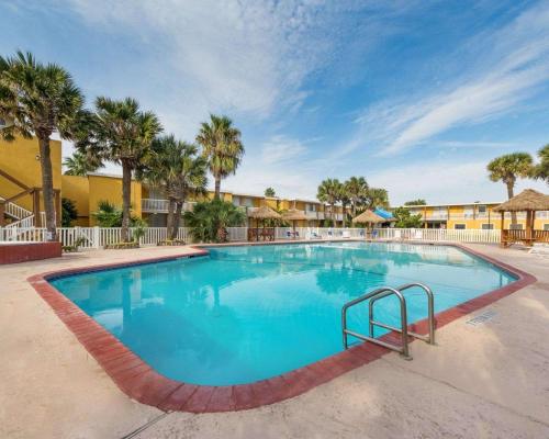 a large swimming pool at a resort with palm trees at Quality Inn & Suites on the Beach in Corpus Christi