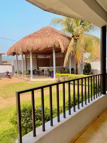 a resort with a thatched roof and a palm tree at Paloma Guest House in Kenema