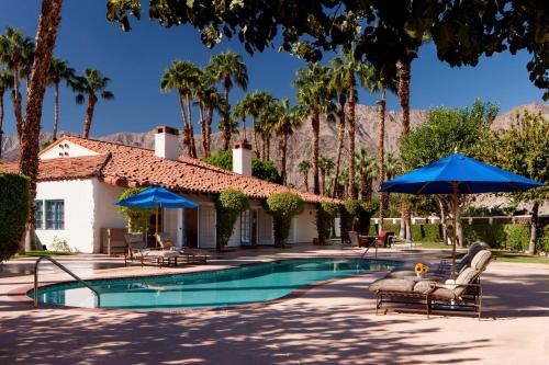 einen Pool mit Stühlen und Sonnenschirmen neben einem Haus in der Unterkunft La Quinta Resort & Club, Curio Collection in La Quinta
