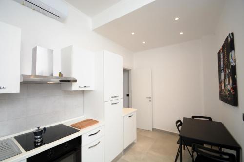 una cucina con armadi bianchi e tavolo nero di Piazza Della Vittoria Apartment a Genova