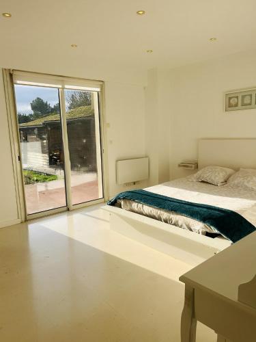 une chambre blanche avec un lit et une grande fenêtre dans l'établissement Villa des Plantes, à Villecresnes