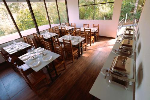 a restaurant with tables and chairs in a room with windows at Elenji Revive Resort in Munnar