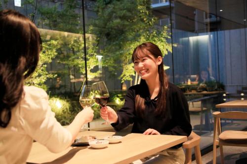 two women sitting at a table with a glass of wine at Richmond Hotel Premier Kyoto Shijo in Kyoto