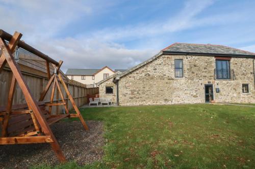 a stone house with a yard with a swing at The Old Cattle Barn in Launceston