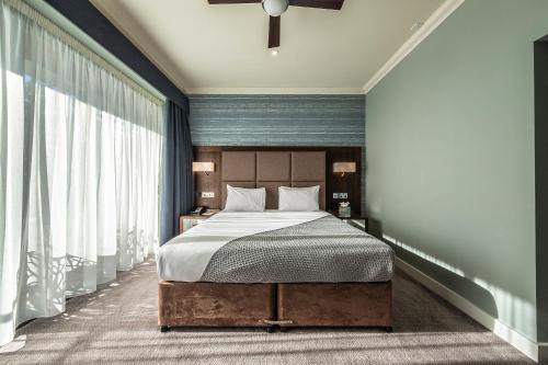 a bedroom with a bed and a large window at Wivenhoe House Hotel in Colchester