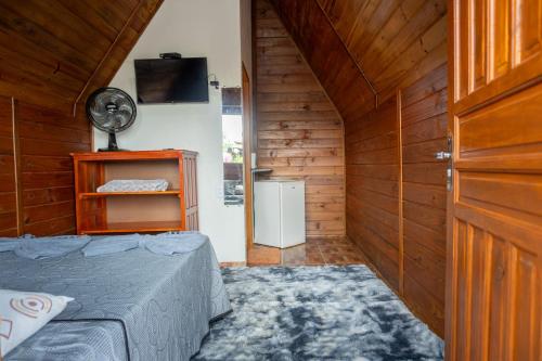 a small room with a bed and a fan at Chalés Carrara in Alto Paraíso de Goiás