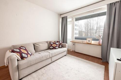 a living room with a couch and a window at 2ndhomes Cozy 1BR Apartment w/ Balcony next to tram stop in Helsinki