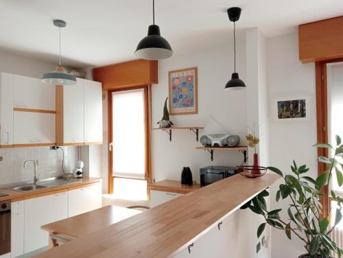 a kitchen with white cabinets and a wooden counter top at Casa Sud vicino a fiera e Pordenone centro in Pordenone