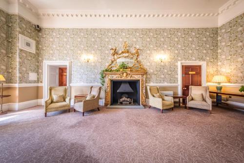 a living room with a fireplace and chairs at Wivenhoe House Hotel in Colchester