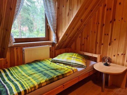een bed in een houten kamer met een raam bij Ferienhaus "BASTEK2" am See mit Kamin & WLAN - Domek Letniskowy BASTEK in Pasym