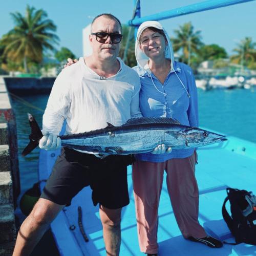 a man and woman standing on a boat holding a fish at Rindali - The speedboat from Malé to the hotel departs at 1130 every Monday Thursday and Saturday and from the hotel to Malé at 0630 and five domestic flights are available every day in Dhaalu Atoll