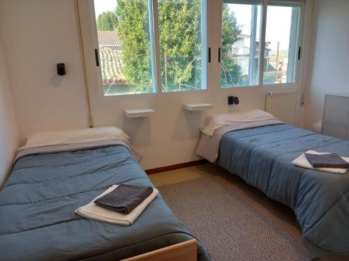 two beds in a room with two windows at Casa Margarida in Allariz