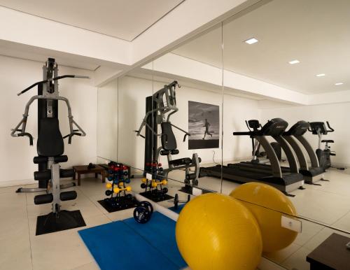 a gym with several tread machines and a mirror at Hotel Cabo Branco Atlântico in João Pessoa