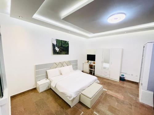 Dormitorio blanco con cama blanca y mesa en Avrum Homes, en Abuja